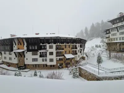 an apartment building in the snow with snow on it at Гранд Манастира Лукс in Pamporovo
