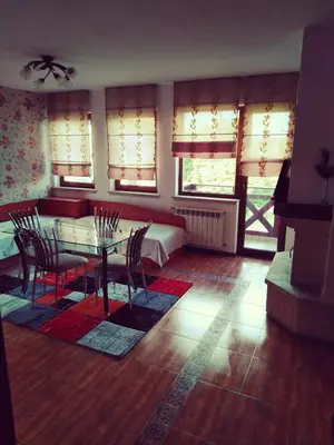 a dining room with a table and chairs and windows at GD Apartament in Bansko