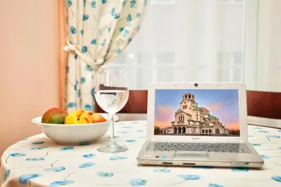 a laptop on a table with a bowl of fruit and a glass of wine at Aurora Oasis - AC & Lift in Vibrant Downtown Sofia by Flat Mаnager in Sofia