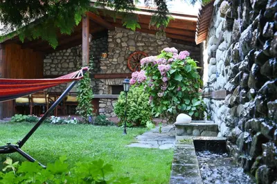 a house with a garden with a rock wall at Marand Villas in Bansko