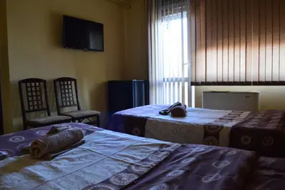 a room with two beds and two chairs and a window at Dionis Hotel in Petrich