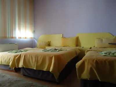 two beds in a room with yellow sheets at Dionis Hotel in Petrich