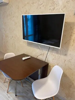a television hanging on a wall with a table and chairs at Colonel apartment 938 in Sofia