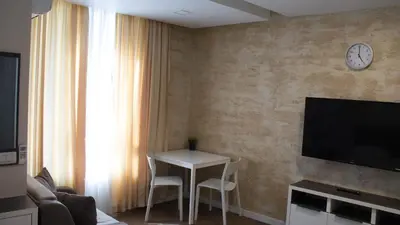 a living room with a table and a clock on a wall at Colonel apartment Luxury in Sofia