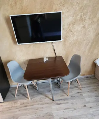 a wooden table with two chairs and a television on a wall at Colonel apartment 953 in Sofia
