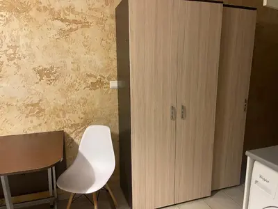 a white chair next to a table and a cabinet at Colonel apartment 956 in Sofia