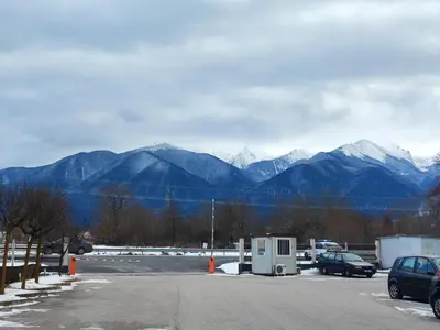 a parking lot with snow capped mountains in the background at Aspen Valley Studio Apartment Аспен Вали студио апартамент in Razlog