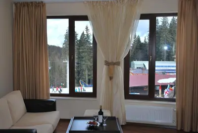 a living room with two large windows and a couch at Spider House Aparthotel in Pamporovo