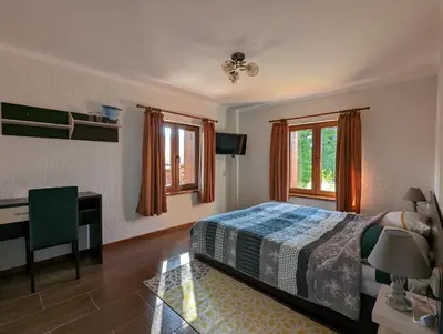 a bedroom with a bed and a desk and window at Къща за гости Феникс in Koprivshtitsa