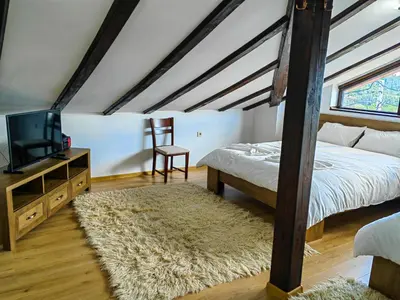 a bedroom with a bed and a television and a rug at Rimovata Kashta Guest House in Leshten