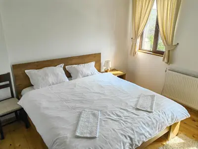 a bedroom with a large white bed with two pillows at Rimovata Kashta Guest House in Leshten