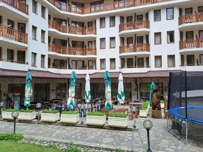a hotel with tables and umbrellas in front of it at Family Studio 302, Villa park in Borovets