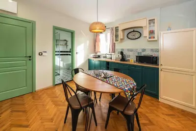a kitchen with green cabinets and a wooden table and chairs at Heart of the City Center Lux Apartment with View in Sofia