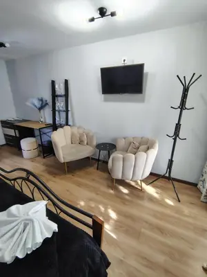 a living room with two chairs and a flat screen tv at Стаи за гости - Цветето на Ангела in Bankya