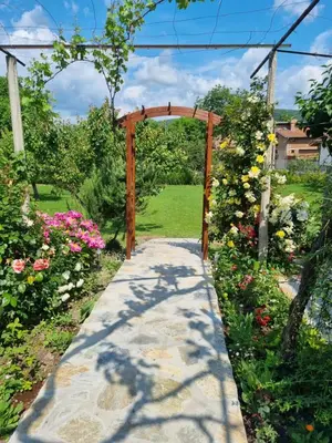 a path through a garden with a wooden arch and flowers at Walnut Cottage 1 in Deredzhik-Kʼoy