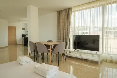 a living room with a table and chairs and a television at апартаменти Пасажио in Sandanski