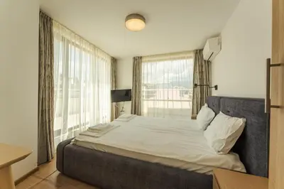 a bedroom with a large bed with a large window at апартаменти Пасажио in Sandanski