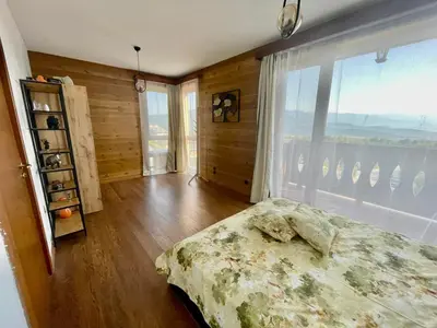 a bedroom with a bed and a large window at Pirin Golf Penthouse Iliyana in Bansko