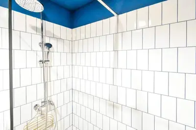 a bathroom with a shower with white tiled walls at 3 Rooms Together Budget Central Stay in Sofia