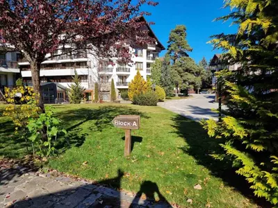 a sign in the grass in front of a building at Borovets Ski&Spa Studio - Semiramida Garden A16 in Borovets