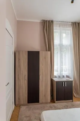 a bedroom with a wooden cabinet and a window at Luxury Apart Vitosha Boulevard in Sofia