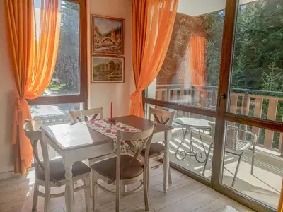 a dining room with a table and chairs and a balcony at Lovely Borovets Apartment in Borovets