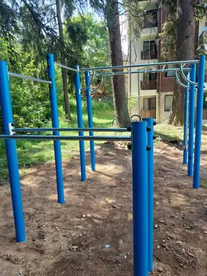 a blue bench in a park with trees and a building at Lovely Borovets Apartment in Borovets