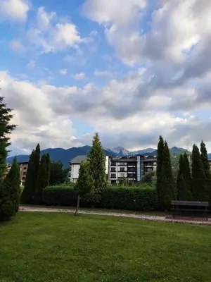 a park with a building and mountains in the background at Aspen Golf Resort Studio I205 in Bansko