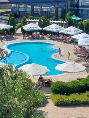 a swimming pool with umbrellas and people sitting around it at Aspen Golf Resort Studio I205 in Bansko
