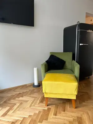 a living room with a yellow chair and a television at Sofia Downtown Boutique Apartment in Sofia