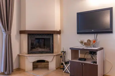 a living room with a fireplace and a flat screen tv at Вила 11 - семейна почивка в сърцето на Балкана in Ribarica