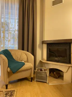 a living room with a chair and a fireplace at Вила 11 - семейна почивка в сърцето на Балкана in Ribarica