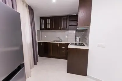 an empty kitchen with wooden cabinets and a sink at Мезонет Пасажио in Sandanski