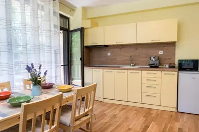 a kitchen with a table and chairs and a refrigerator at Bendida Park in Velingrad