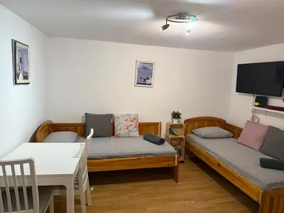 a room with two beds and a table and a tv at Peaceful Riverside Studio with private Garden Center Parking in Plovdiv