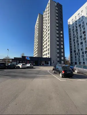 a parking lot with cars parked in front of two tall buildings at Mountain View Apartment 1 + Parking in Sofia