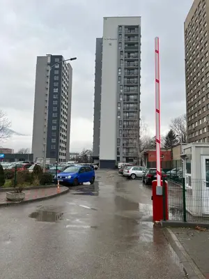 a parking lot with two tall buildings and a blue car at City View Apartment + Parking in Sofia