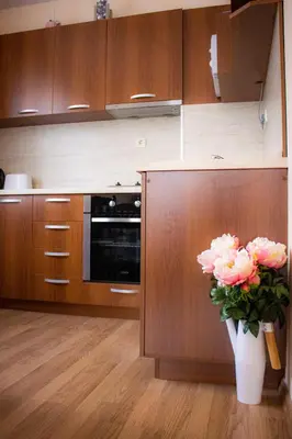 a kitchen with wooden cabinets and a vase of pink flowers at GO GO Holiday in Borovets