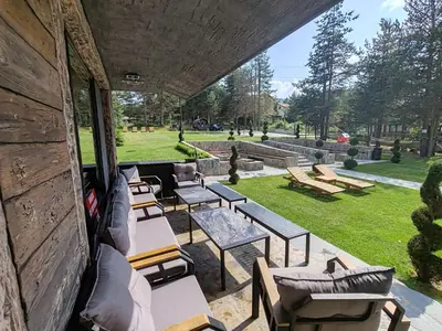 an outdoor patio with tables and chairs in a park at Вила АМРИТА in Tsigov Chark