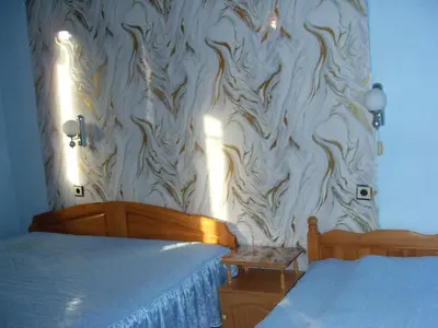 a bedroom with a white wall with a wood pattern at Guest House Rimski Most in Melnik