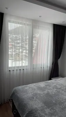 a bedroom with a bed and a window with curtains at ORION APARTMENTS in Chepelare