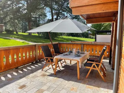 a table and chairs with an umbrella on a deck at Allure in Pirin Golf in Razlog