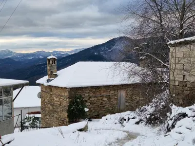 a building covered in snow with mountains in the background at Вила 'Гнездото', Villa 'The nest', Rhodope mountains, Banite in Vishnevo