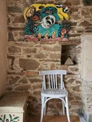 a white chair sitting next to a wall with a painting at Вила 'Гнездото', Villa 'The nest', Rhodope mountains, Banite in Vishnevo