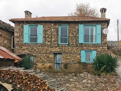 a stone house with blue windows and a stone wall at Вила 'Гнездото', Villa 'The nest', Rhodope mountains, Banite in Vishnevo