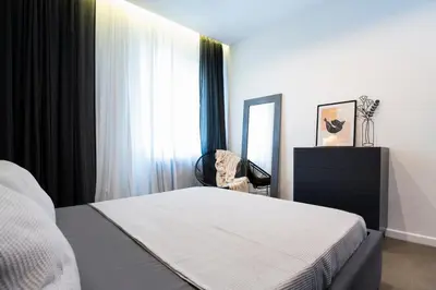 a bedroom with a bed and a mirror and a chair at Lozenets Modern Apartment Tranquil & Central in Sofia