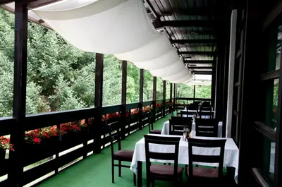 a restaurant with white tables and chairs and windows at Everest Hotel in Etropole