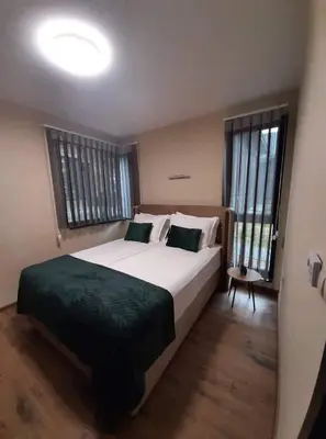 a bedroom with a large bed and two windows at Вила Bora Vista 2 in Tsigov Chark