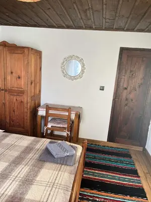 a bedroom with a bed and a chair and a mirror at Къща за гости Близнаците in Leshten