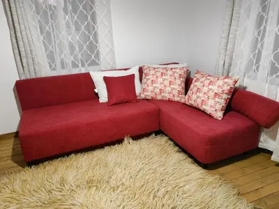 a red couch with pillows on top of a rug at Къща за гости Близнаците in Leshten